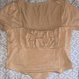 tan crop top with ruffles in middle and a v on the bottom of the shirt